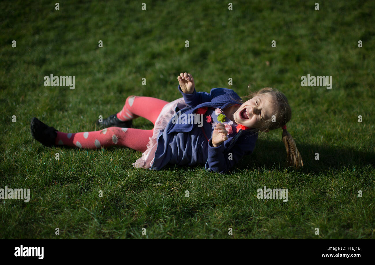 A young girl rolls down a hill in Greenwich, England, UK Stock Photo