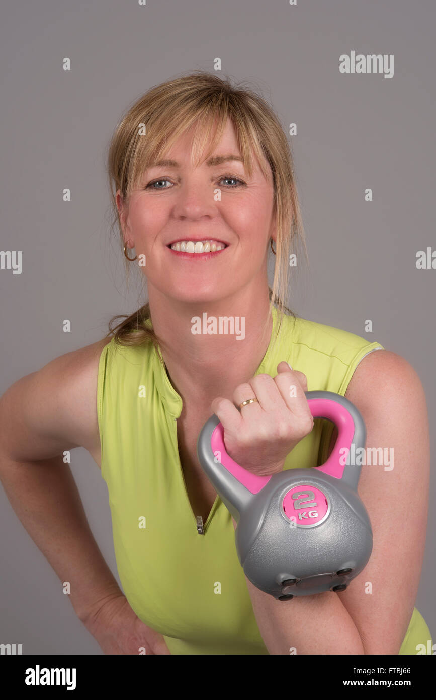 Woman exercising with a kettle bell weight weighing 2 Kg Stock Photo