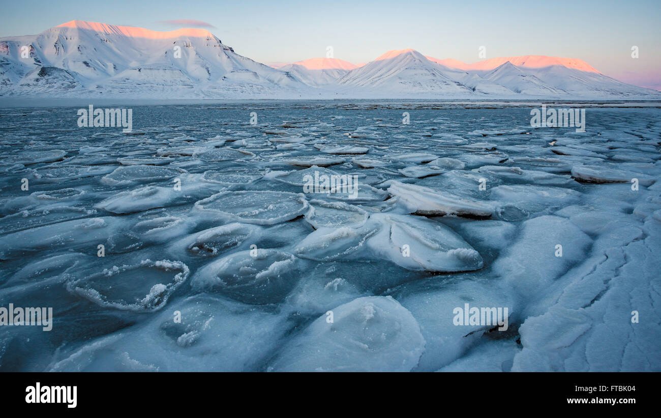 Sunset frozen shoreline at Sjøskrenten beach with views to Hiorthfjellet, Longyearbyen, Spitsbergen, Svalbard. Stock Photo