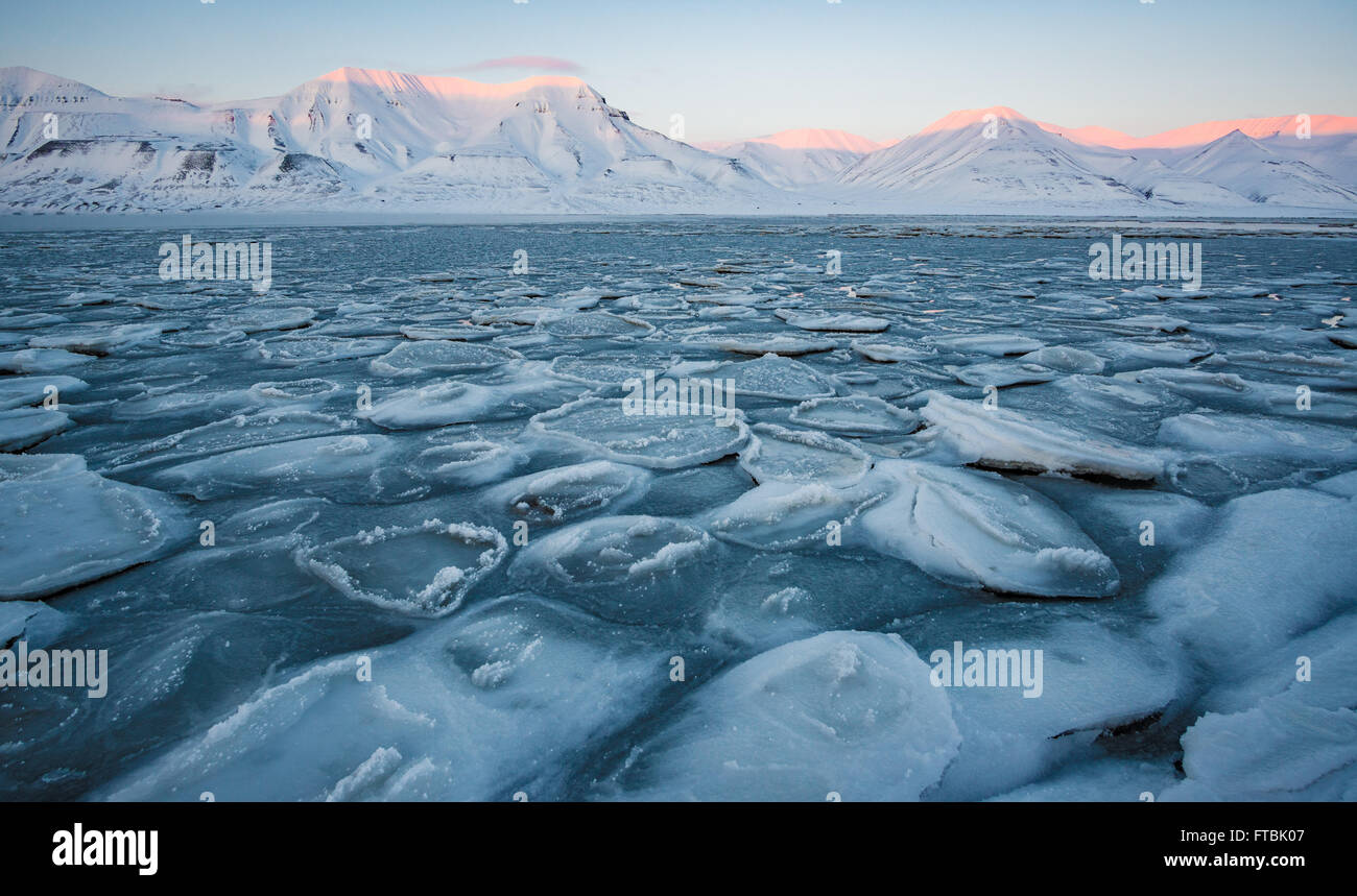 Sunset frozen shoreline at Sjøskrenten beach with views to Hiorthfjellet, Longyearbyen, Spitsbergen, Svalbard. Stock Photo