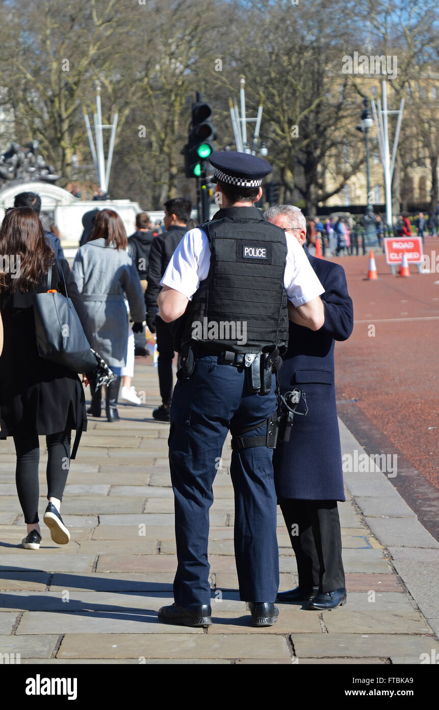 Armed policeman in London with tourists outside of Buckingham Palace Stock Photo
