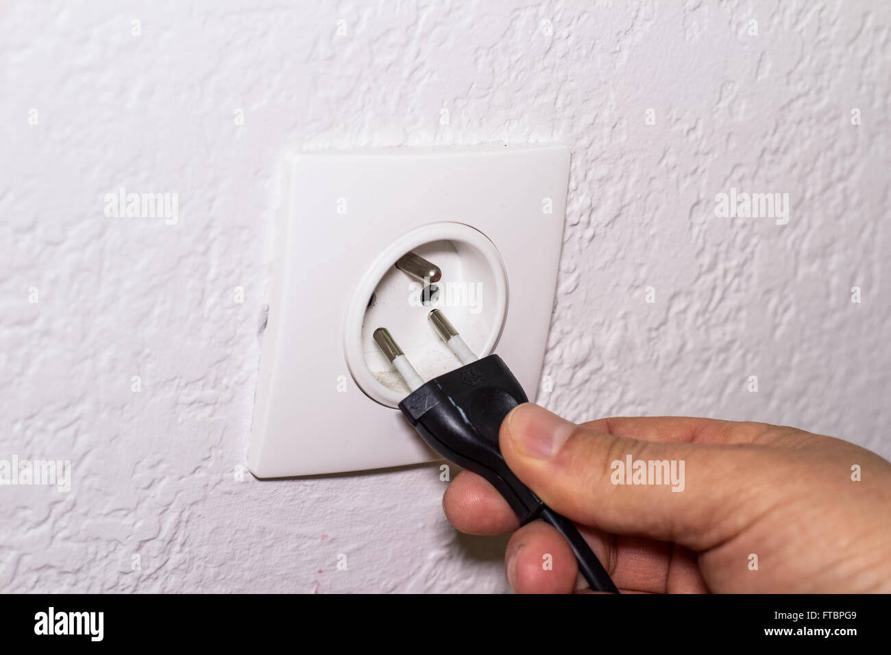 Hand plugs power cord in wall socket Stock Photo Alamy