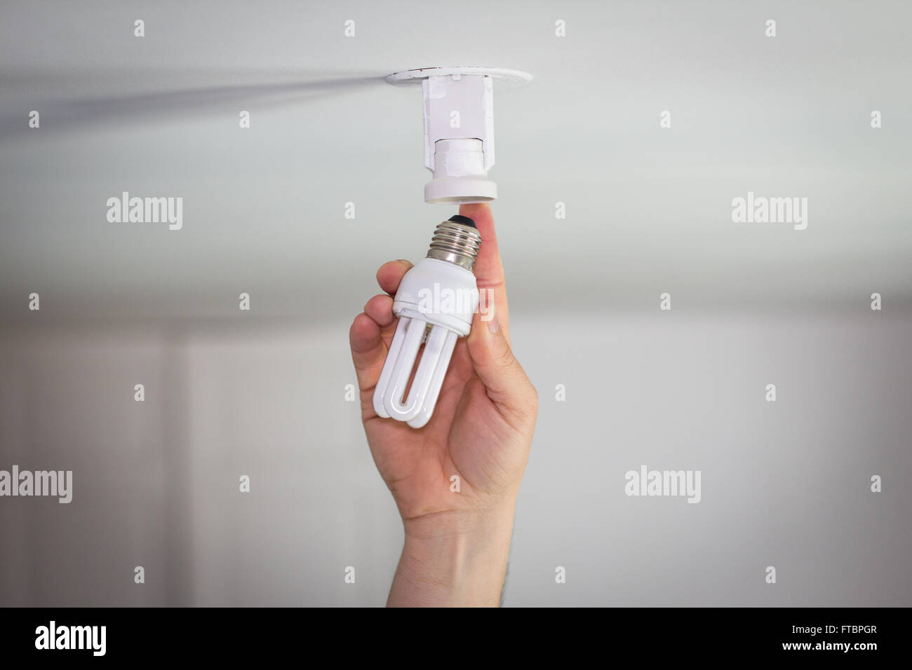 Hand puts ecological light bulb in socket Stock Photo Alamy