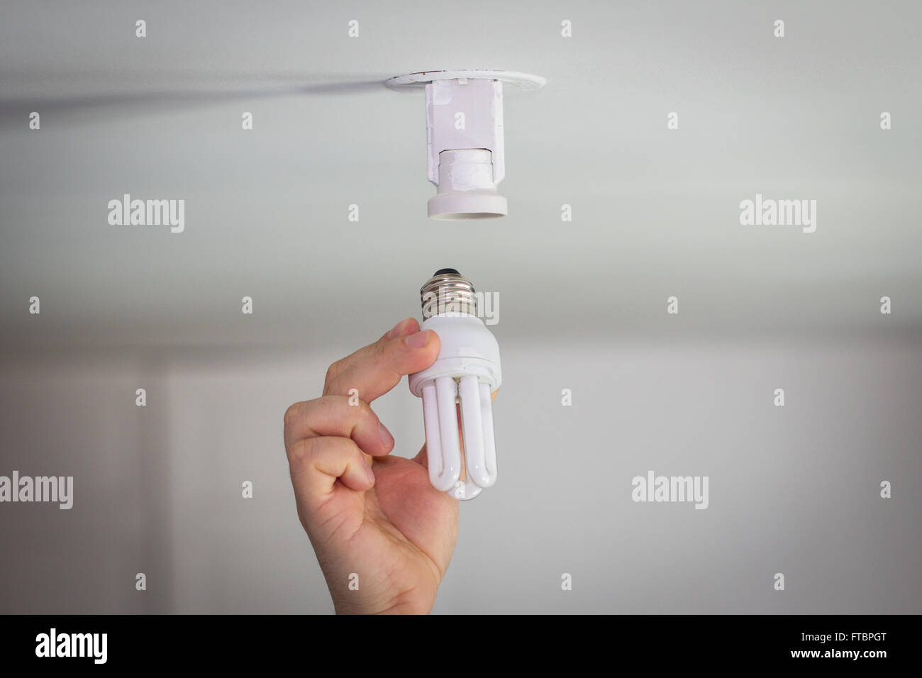Hand puts ecological light bulb in socket Stock Photo Alamy