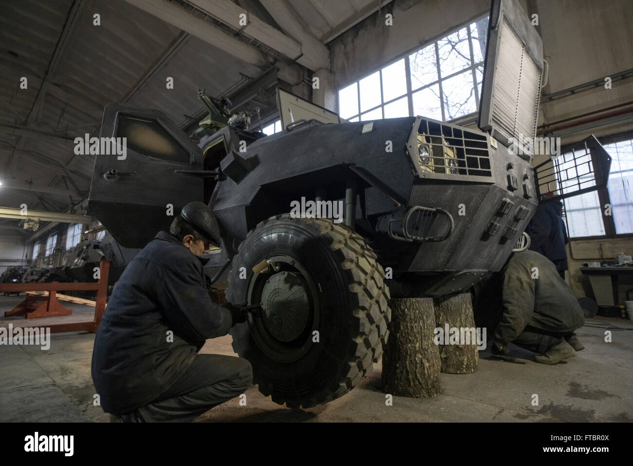 Workers carry out work on the wheels of a DozorB armoured personnel