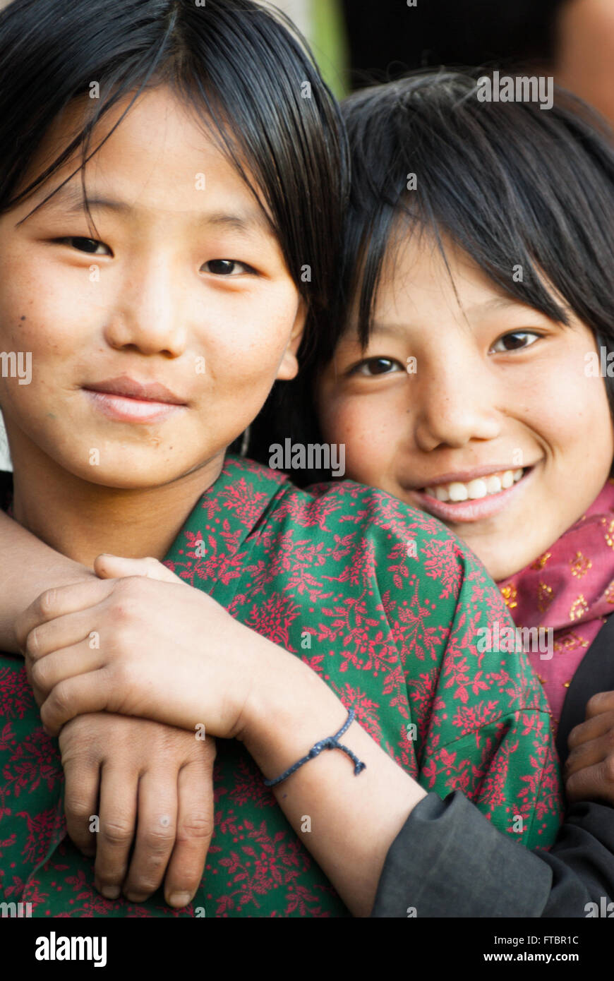 Two young Bhutanese girl friends wearing traditional kira (long wrap dress) and jacket in Nimshong Village, southern Bhutan Stock Photo