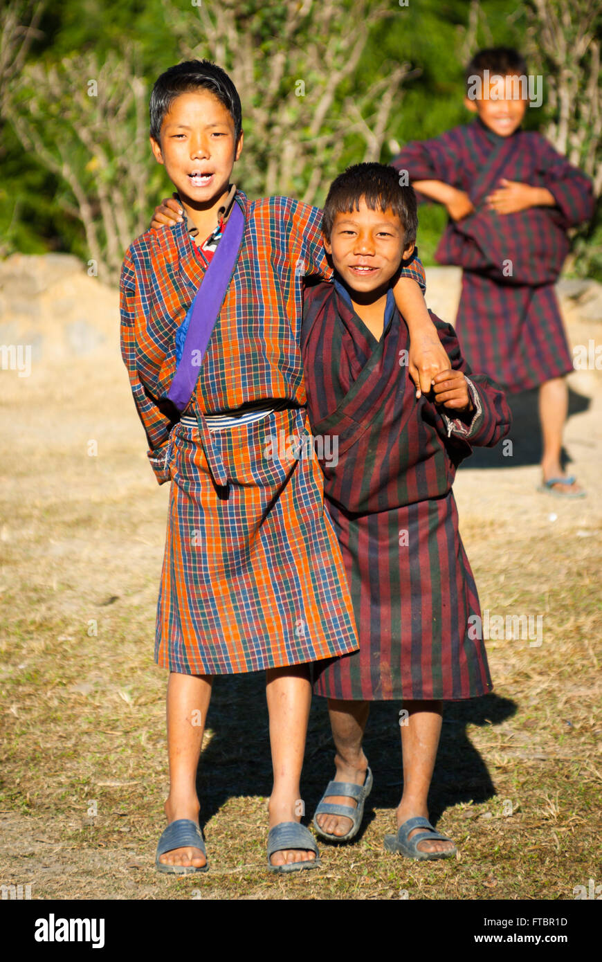 Young Bhutanese boys wearing traditional striped gho (robe) in Nimshong Village, southern Bhutan Stock Photo