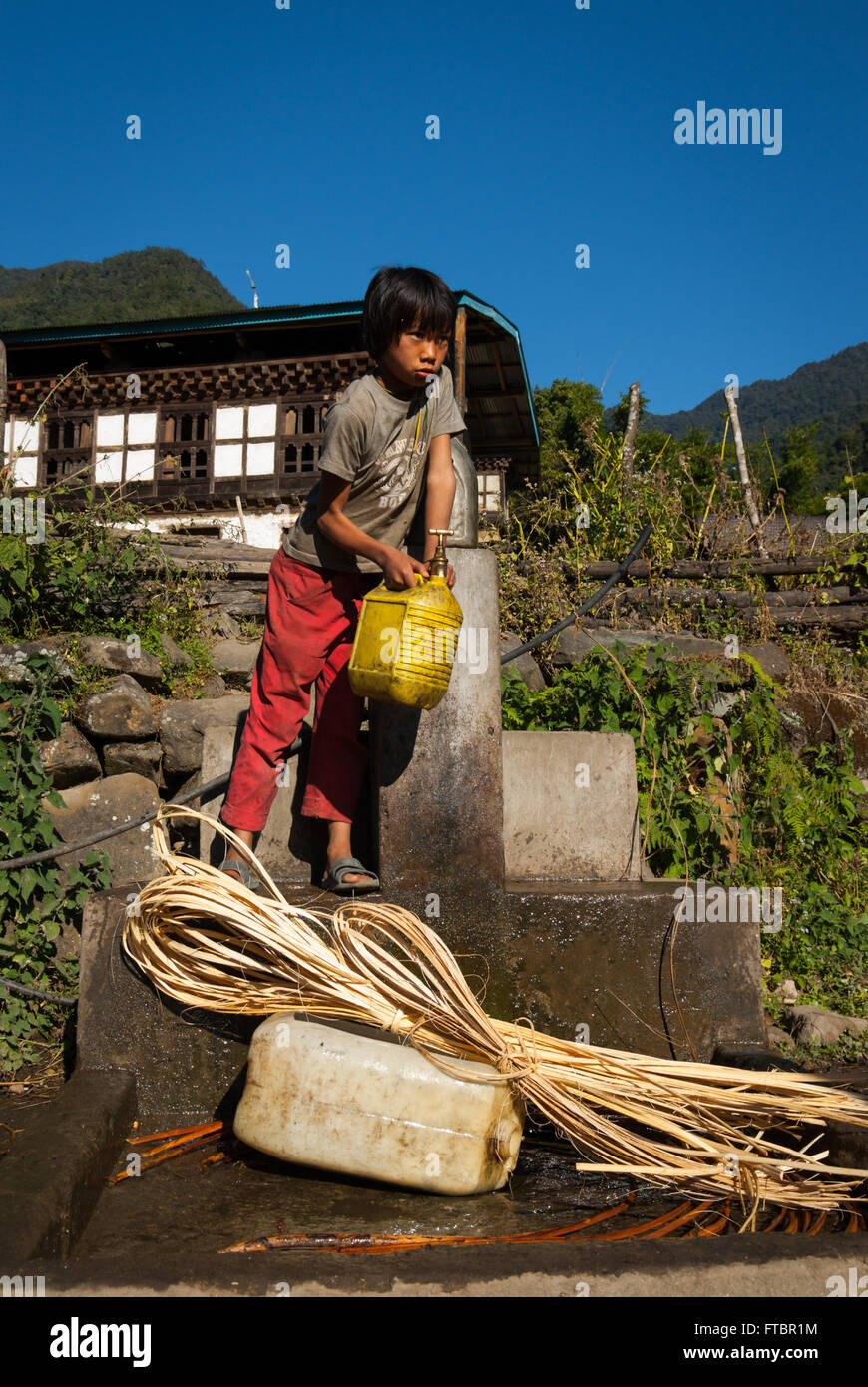 Girl collecting water from a community tap in Nabji Village, southern Bhutan Stock Photo