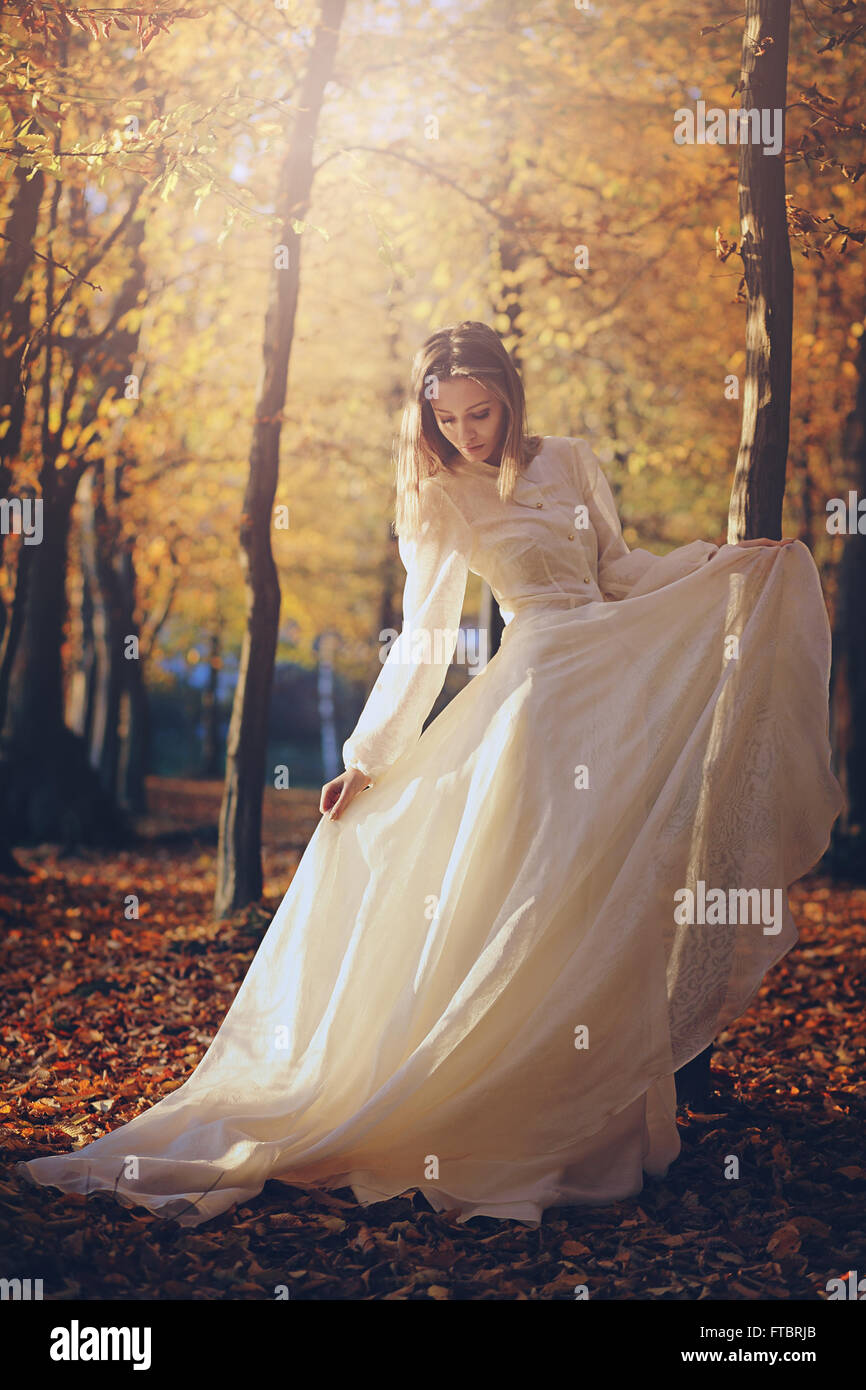 Beautiful woman with victorian dress in autumn woods . Sunset light Stock Photo