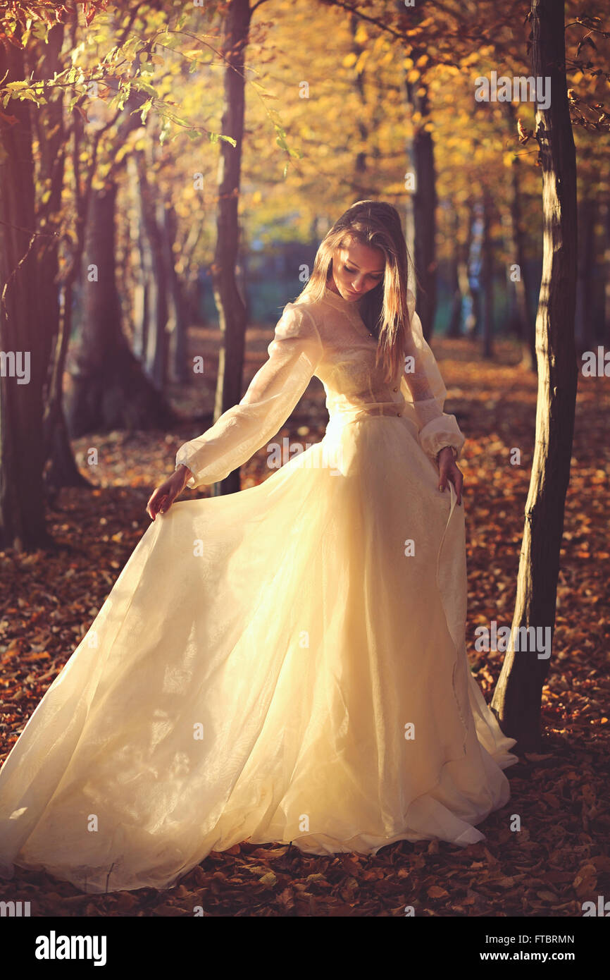 Beautiful woman with victorian dress in sunset light. Autumn leaves Stock Photo