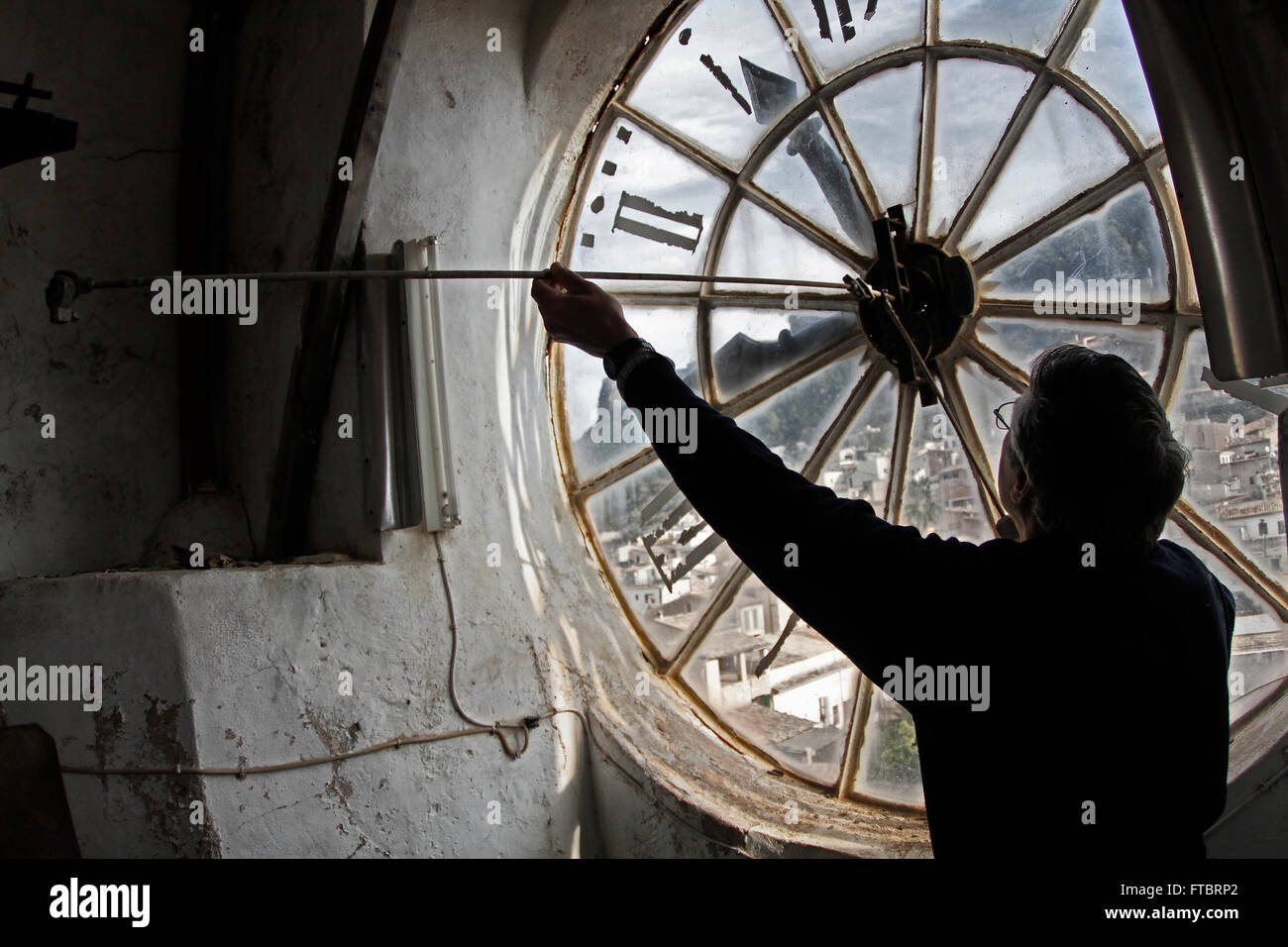 Person playing the clock in the church. The old church is in a village in Sierra Tramuntana in Mallorca in the Balearic Islands. Stock Photo