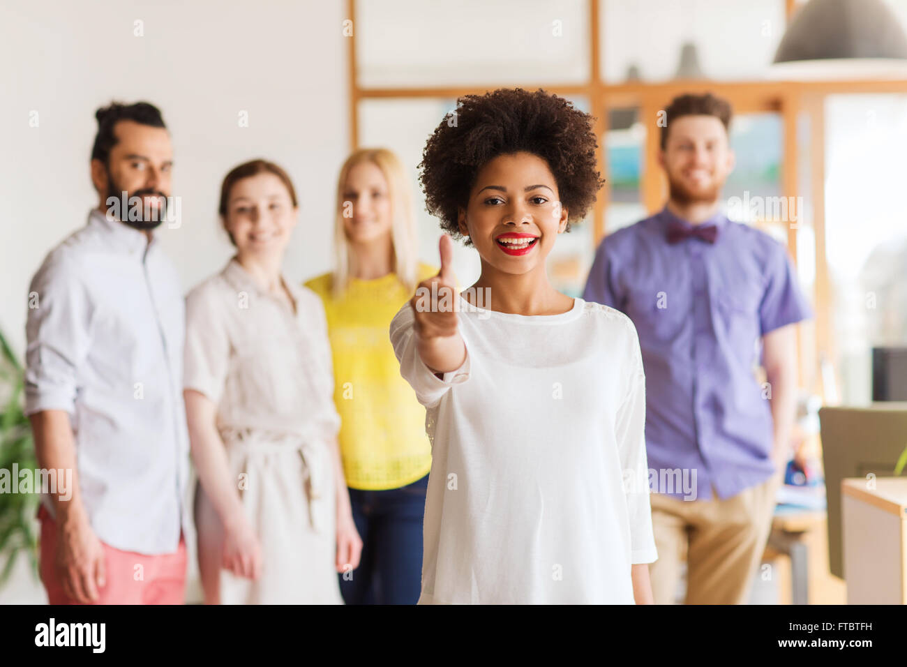 woman showing thumbs up over creative office team Stock Photo - Alamy