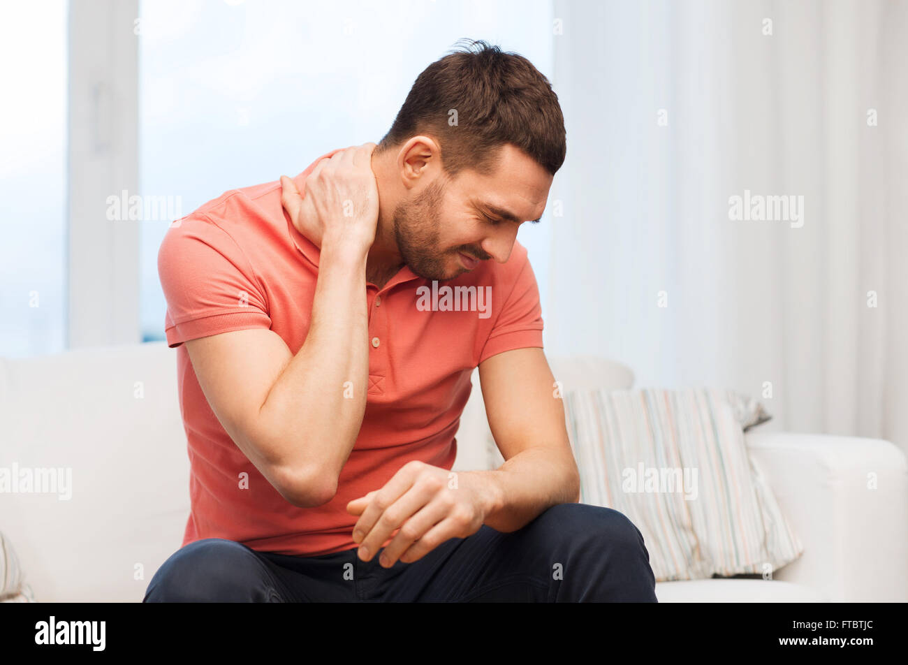 unhappy man suffering from neck pain at home Stock Photo - Alamy