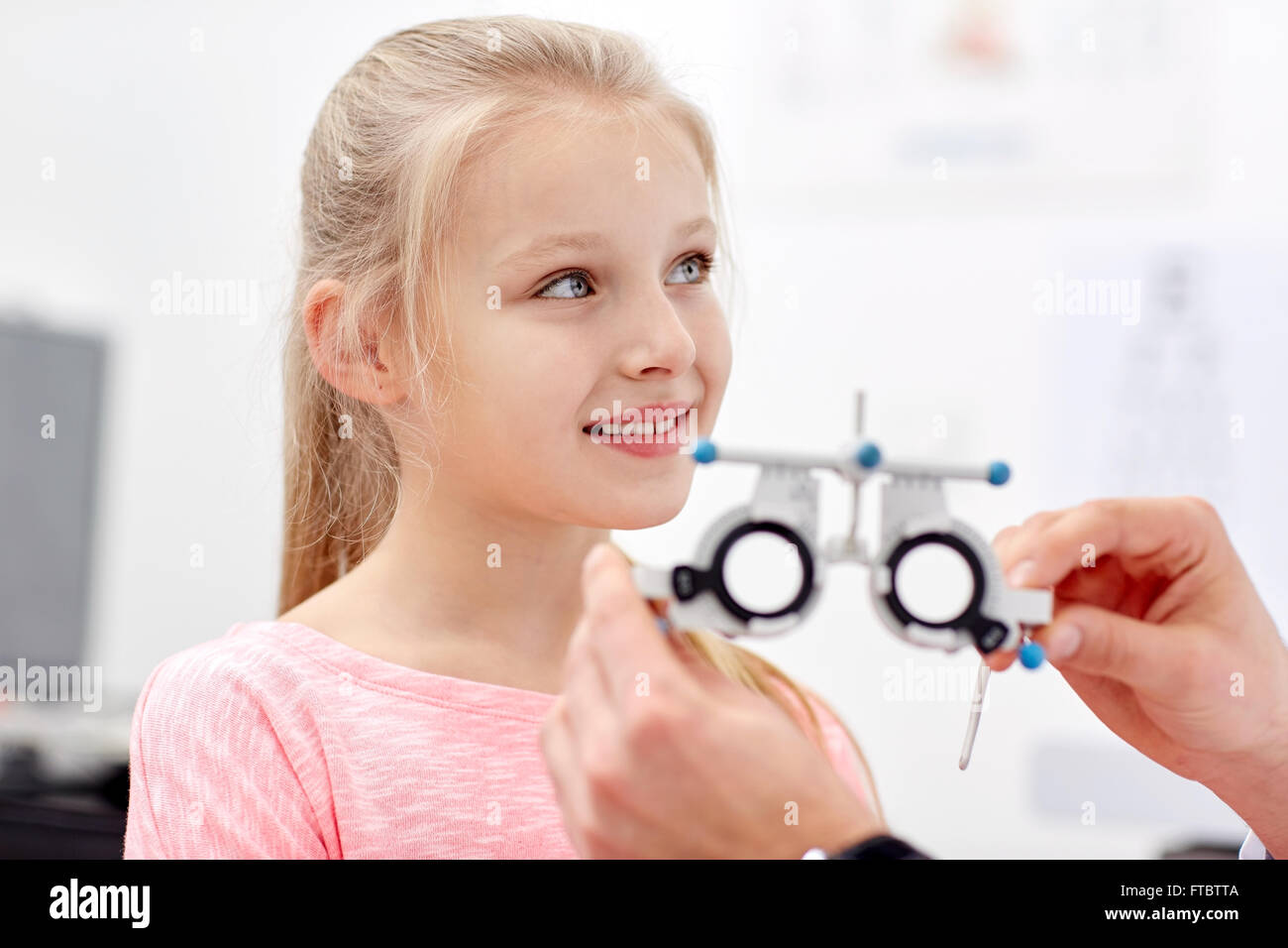optician with trial frame and girl at clinic Stock Photo
