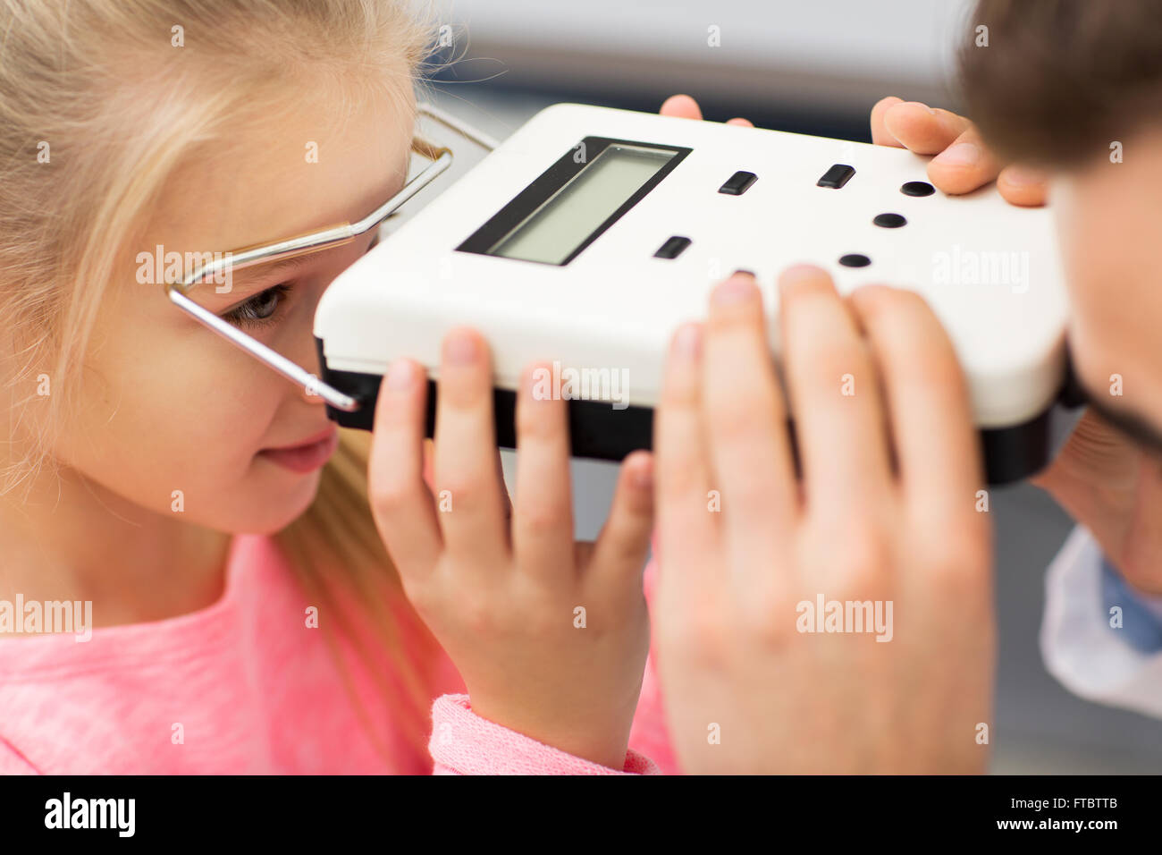 optician with pupillometer and girl at eye clinic Stock Photo