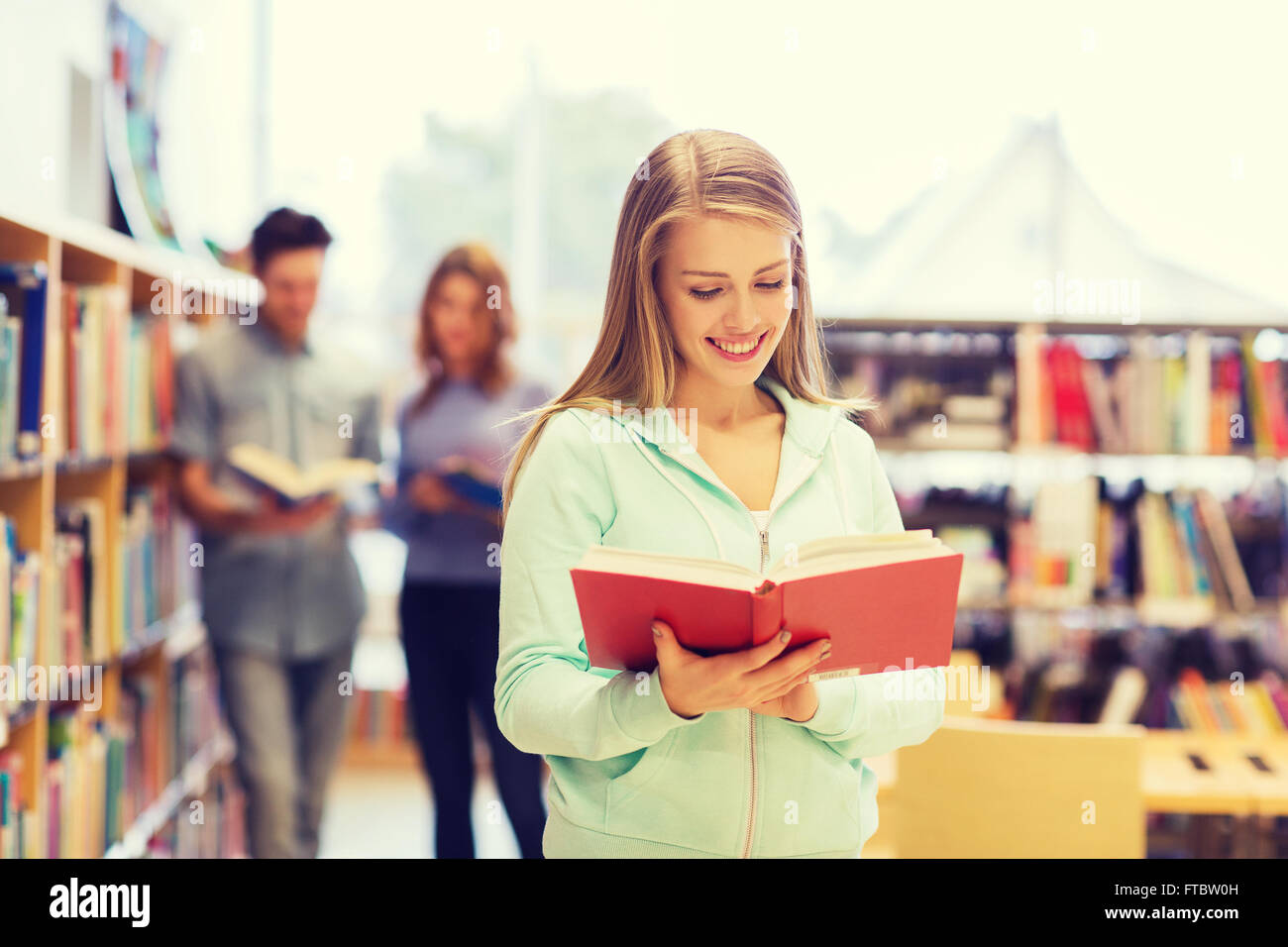 happy student girl or woman with book in library Stock Photo - Alamy