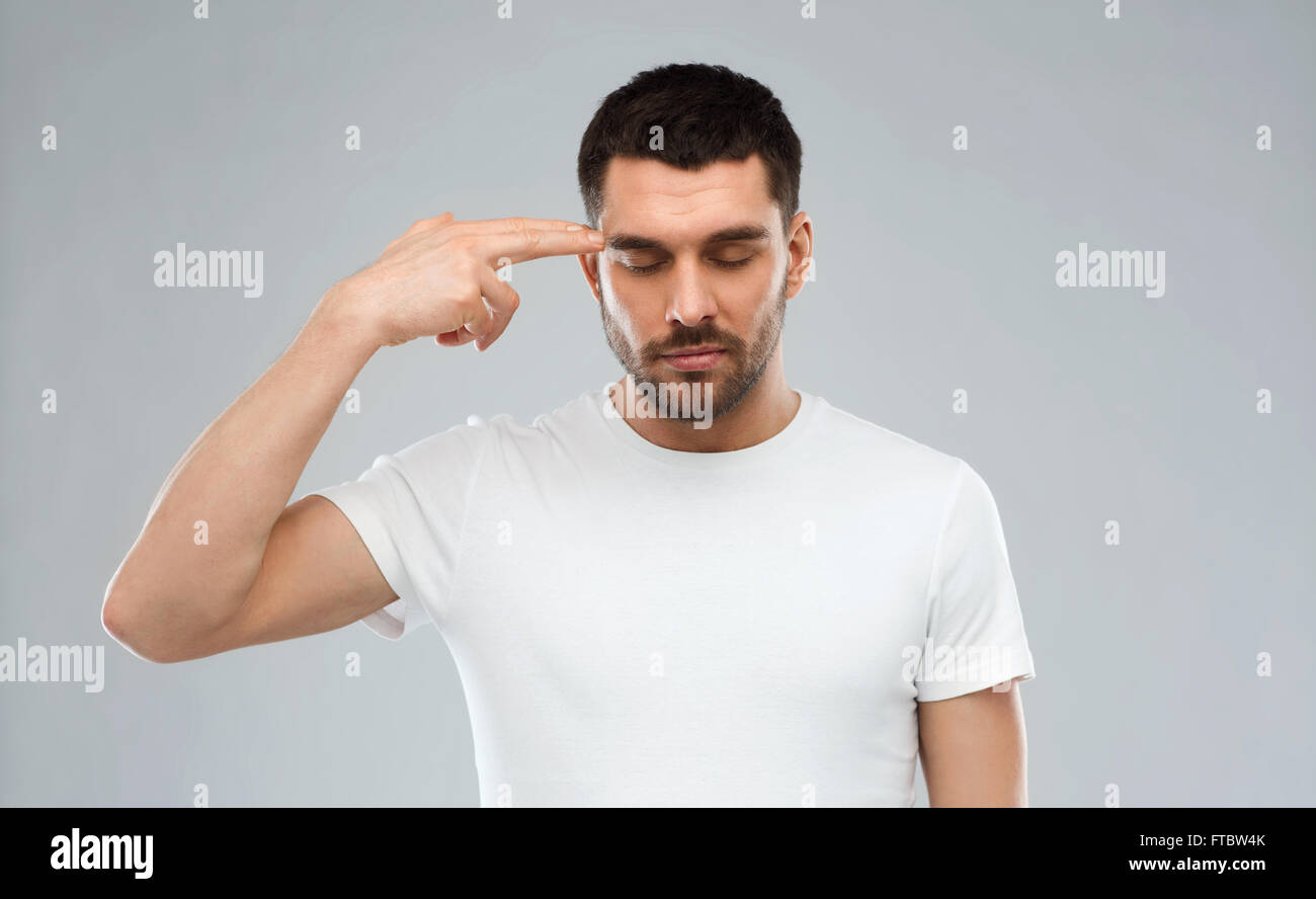 man making finger gun gesture over gray background Stock Photo
