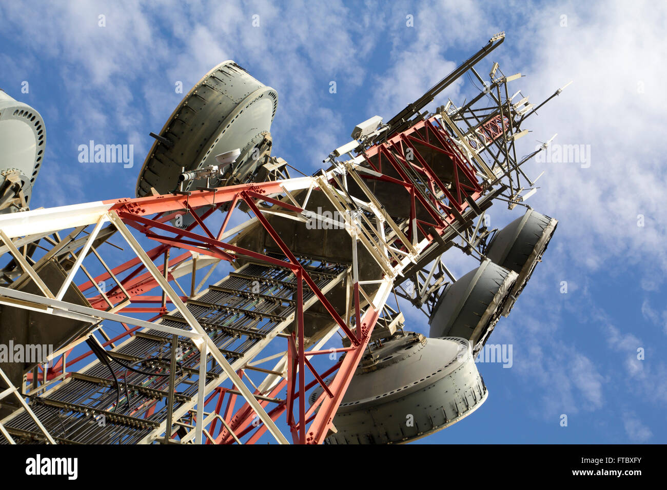 Telecommunications tower against blue sky, in red and white Stock Photo