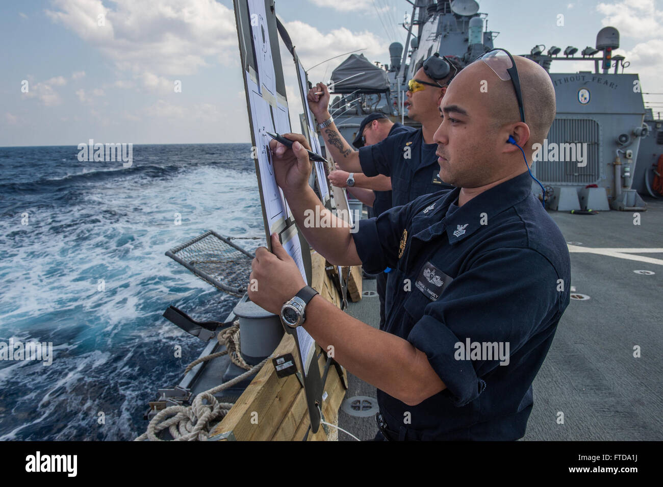150314-N-XB010-098 MEDITERRANEAN SEA (March 14, 2015) Fire Controlman 1st Class Joshua Ramsey from Woodbridge, Virginia, front, Chief Gunner’s Mate Vuong Nguyen from Houston, back, grade targets during gun qualifications on the flight deck of USS Laboon (DDG 58) March 14, 2015. Laboon, an Arleigh Burke-class guided-missile destroyer, homeported in Norfolk, is conducting naval operations in the U.S. 6th Fleet area of operations in support of U.S. national security interests in Europe. (U.S. Navy photo by Mass Communication Specialist 3rd Class Desmond Parks/Released) Stock Photo