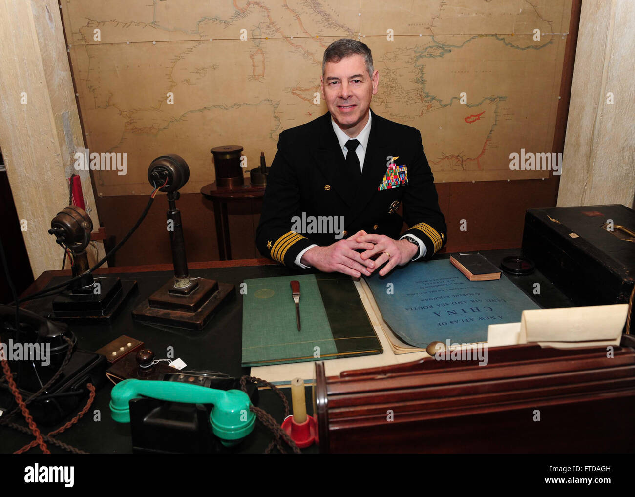 150324-N-BD333-093 PORTSMOUTH, United Kingdom (March 24, 2015) Capt. Daniel Grieco, commanding officer aboard the aircraft carrier USS Theodore Roosevelt (CVN 71) sits in Sir Winston S. Churchill’s chair in his office-bedroom during a tour of the Churchill War Rooms museum in London, March 24, 2015. Theodore Roosevelt Carrier Strike Group (TRCSG) leadership, including Cdr. Christine O'Connell, commanding officer of the Arleigh-Burke class guided missile destroyer USS Winston S. Churchill (DDG 81), attended the tour of the museum. Churchill, home-ported in Norfolk, is conducting naval operation Stock Photo