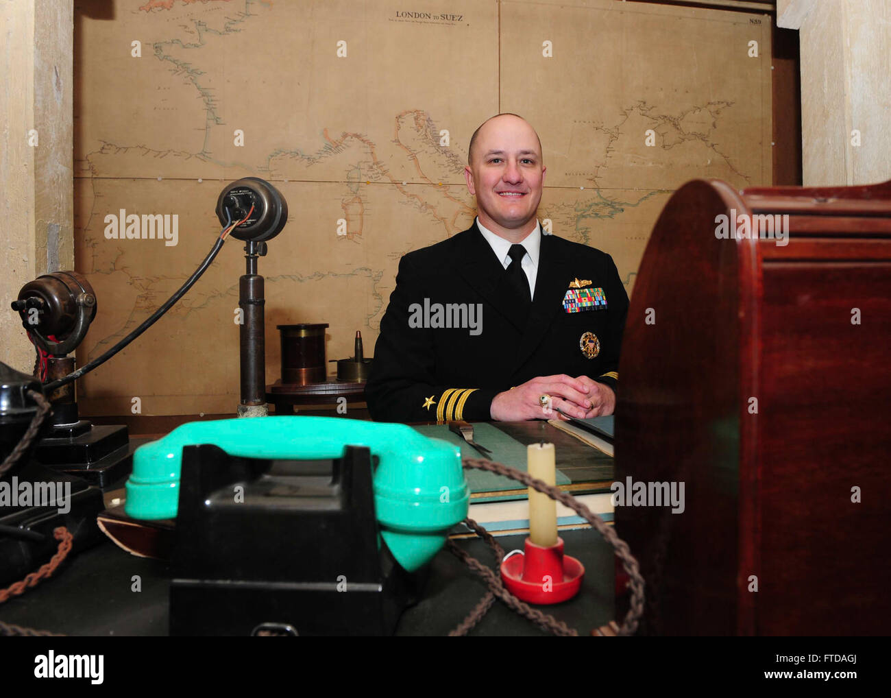 150324-N-BD333-095 PORTSMOUTH, United Kingdom (March 24, 2015) Cmdr. Paul Allgeier, executive officer of the Arleigh-Burke class guided missile destroyer USS Winston S. Churchill (DDG 81), sits in Sir Winston S. Churchill’s chair in his office-bedroom during a tour of the Churchill War Rooms museum in London, March 24, 2015. Theodore Roosevelt Carrier Strike Group (TRCSG) leadership also attended the tour of the museum. Churchill, home-ported in Norfolk, is conducting naval operations in the U.S. 6th Fleet area of operations in support of U.S. national security interests in Europe. (U.S. Navy  Stock Photo