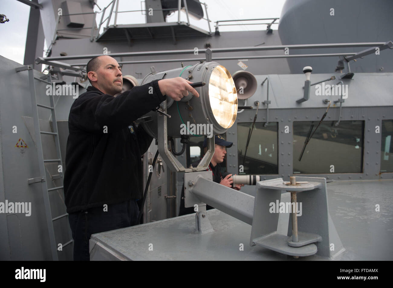 150326-N-ZE250-040 MEDITERRANEAN SEA (March 26, 2015) Chief Quartermaster Kevin Ortega, from Astoria, Oregon, uses a 12-inch searchlight to communicate in Morse Code with Hellenic Navy Ship HS Themistokles (F 465) during a passing exercise March 26, 2015. USS Jason Dunham (DDG 109) Jason Dunham, an Arleigh Burke-class guided-missile destroyer homeported in Norfolk, is conducting naval operations in the U.S. 6th Fleet area of operations in support of U.S. national security interests in Europe. (U.S. Navy photo by Mass Communication Specialist 3rd Class Weston Jones/Released) Stock Photo