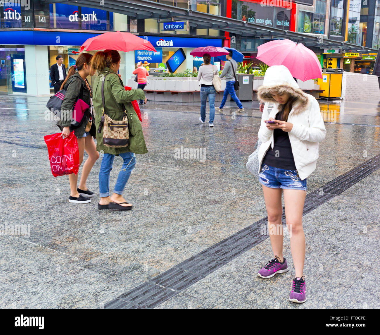 girl texting in the rain queen st mall brisbane Stock Photo