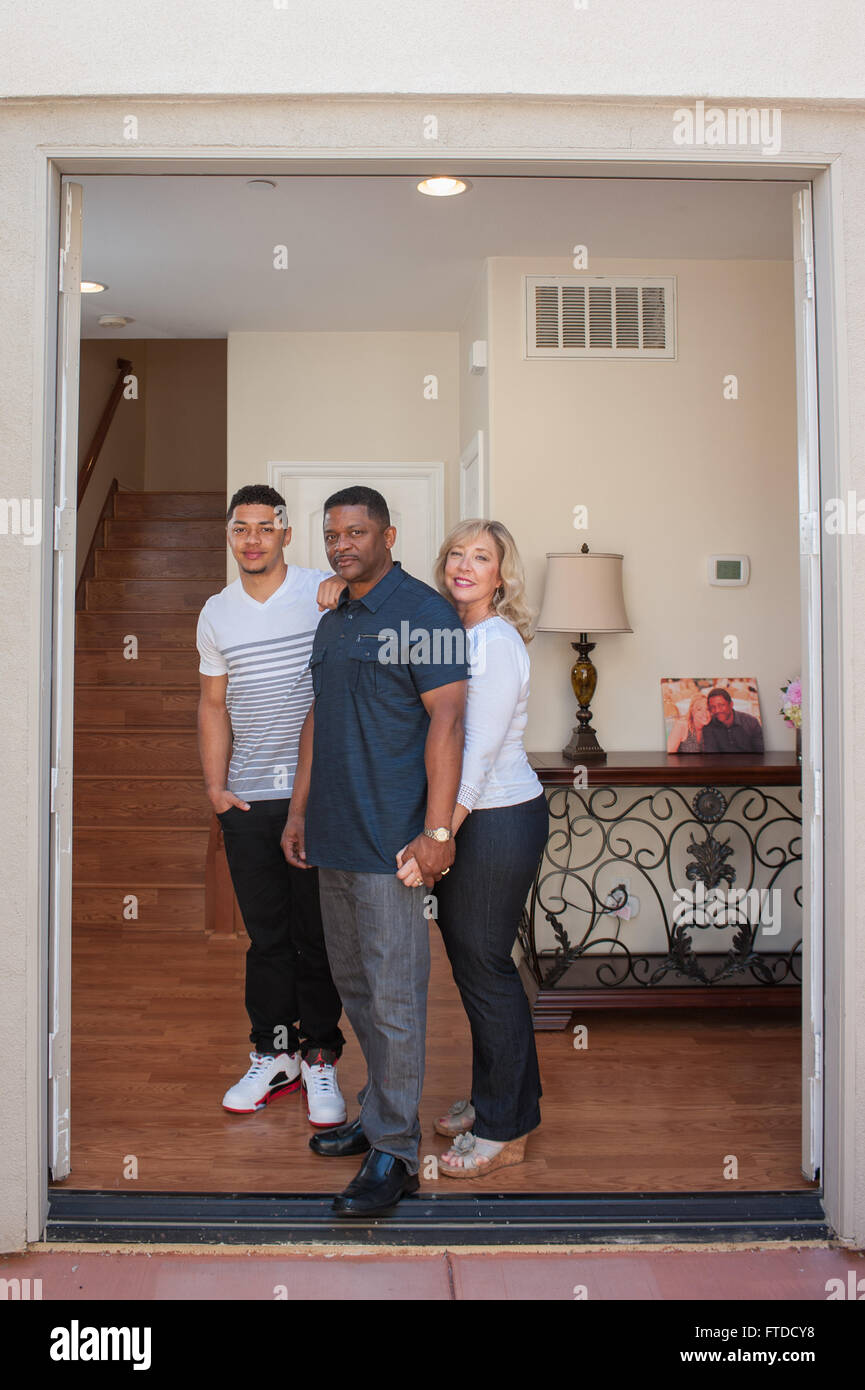 Happy mixed ethnic family posed in inside entry way. Stock Photo