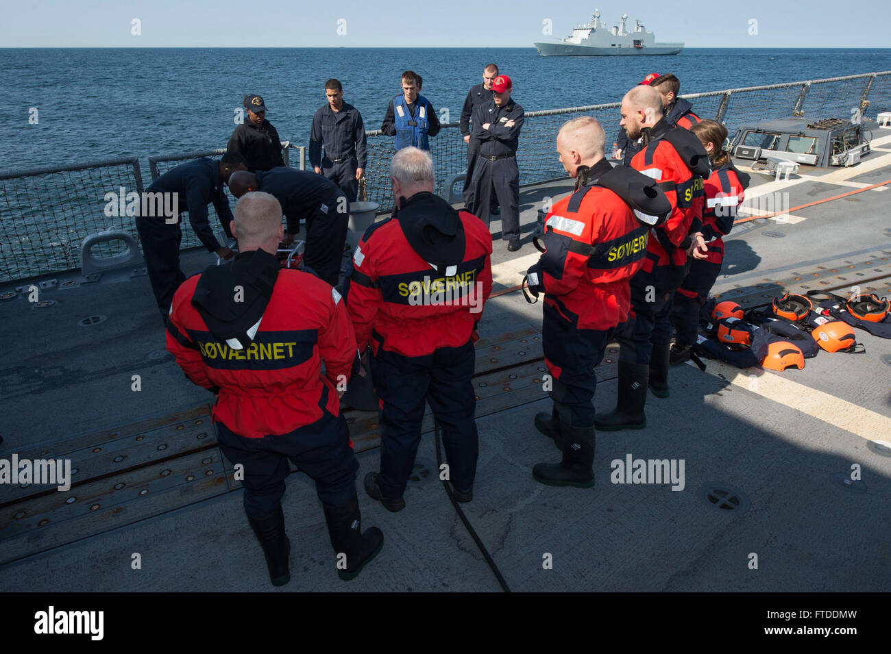 150613-N-ZE250-018 BALTIC SEA (June 13, 2015) Danish Navy sailors from the HDMS Absalon (L16) observe U.S. Sailors setting up a P-100 firefighting pump on the flight deck of USS Jason Dunham (DDG 109) June 13, 2015. Jason Dunham, an Arleigh Burke-class guided-missile destroyer homeported in Norfolk, is participating in exercise Baltic Operations (BALTOPS) 2015. BALTOPS is an annually recurring multinational exercise designed to enhance flexibility and interoperability, as well as demonstrate resolve of Allied and partner forces to defend the Baltic region. (U.S. Navy photo by Mass Communicatio Stock Photo