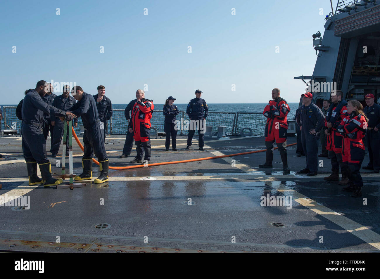 150613-N-ZE250-030 BALTIC SEA (June 13, 2015) Danish Navy sailors from the HDMS Absalon (L16) observe U.S. Navy Sailors patching a simulated ruptured pipe on the flight deck of USS Jason Dunham (DDG 109) June 13, 2015. Jason Dunham, an Arleigh Burke-class guided-missile destroyer homeported in Norfolk, is participating in exercise Baltic Operations (BALTOPS) 2015. BALTOPS is an annually recurring multinational exercise designed to enhance flexibility and interoperability, as well as demonstrate resolve of Allied and partner forces to defend the Baltic region. (U.S. Navy photo by Mass Communica Stock Photo