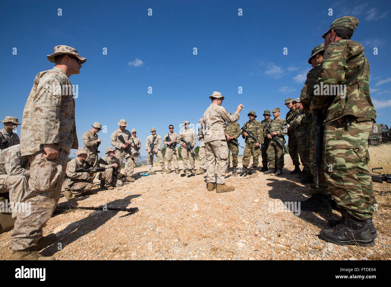150626-M-YH418-012: VOLOS, Greece (June 26, 2015) – Staff Sgt. Jeff Stockton, center, an explosive ordnance disposal technician with the 24th Marine Expeditionary Unit (MEU), gives a class on different types of IEDs to a group of Marines with India Company, Battalion Landing Team 3rd Battalion, 6th Marine Regiment, 24th Marine Expeditionary Unit, and Greek Marines with the 521st Marine Battalion at a training site near Volos, Greece, June 26, 2015 as part of a bilateral training exercise. The 24th MEU is embarked on the ships of the Iwo Jima Amphibious Ready Group and is conducting naval opera Stock Photo