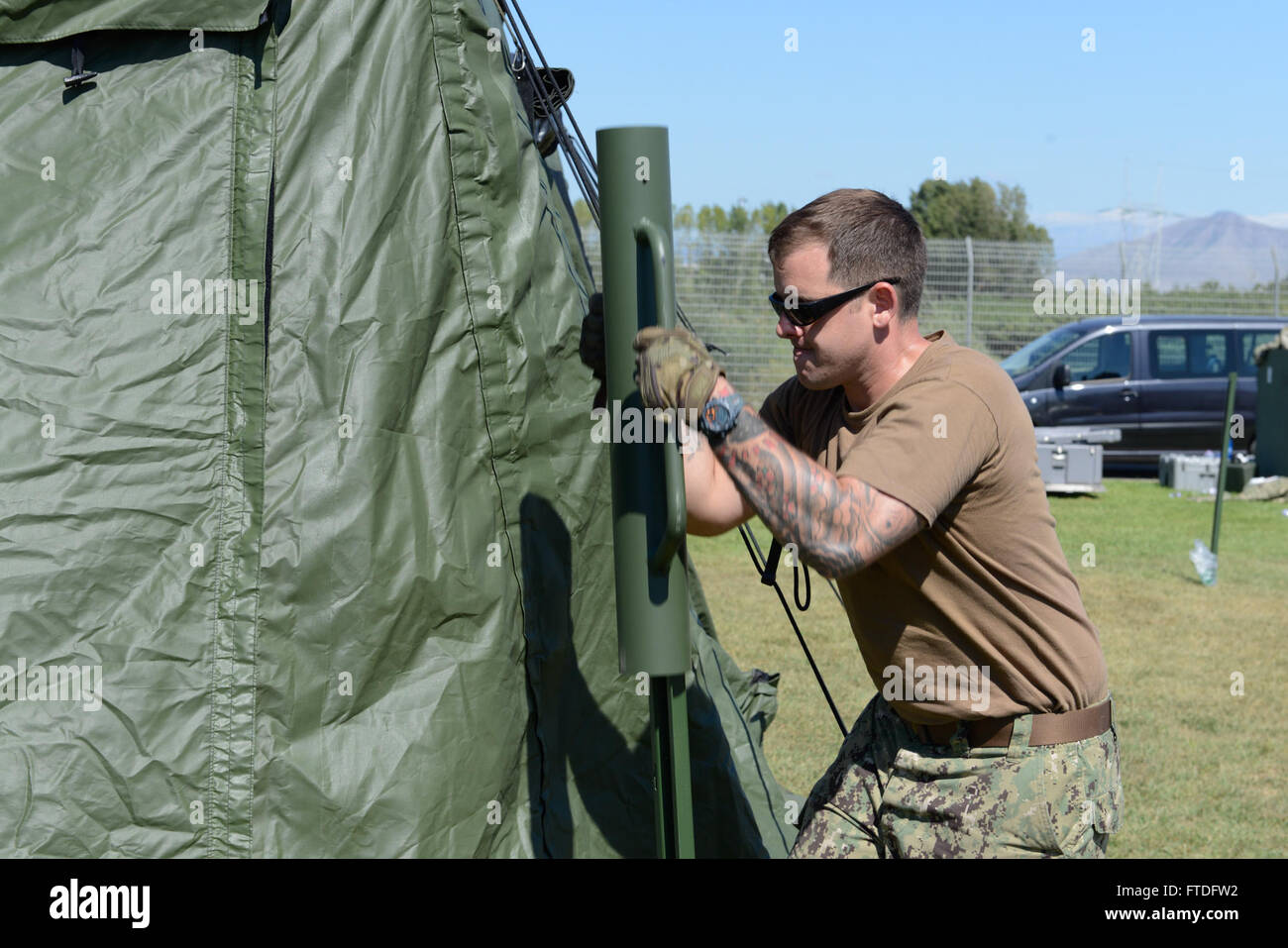 150921-N-UE250-036 GRICIGNANO, Italy (Sept. 21, 2015) Construction Electrician 1st Class Damon Gleason, assigned to Commander, Naval Forces Europe Det. Maritime Ashore Support Team (MAST), uses a post driver to secure a post for the set-up of a c-wire fence around a mobile command center on U.S. Naval Support Activity Naples, Italy Sept. 21, 2015. MAST is currently conducting a Continuity of Operations Planning and crisis management field training exercise. (U.S. Navy photo by Mass Communication Specialist 2nd Class Corey Hensley/Released) Stock Photo