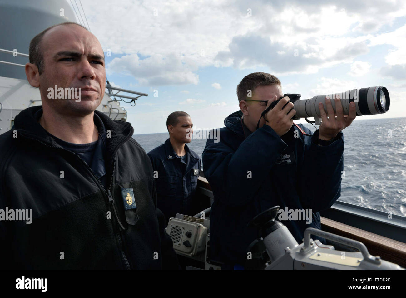 151231-N-XT273-017 MEDITERRANEAN SEA (Dec. 31, 2015) Ship's Nautical or Otherwise Photographic Interpretation and Examination team Sailors photograph a contact from the port bridgewing aboard USS Ross (DDG 71) in the Mediterranean Sea Dec. 31, 2015. Ross, an Arleigh Burke-class guided-missile destroyer, forward deployed to Rota, Spain, is conducting a routine patrol in the U.S. 6th Fleet area of operations in support of U.S. national security interests in Europe. (U.S. Navy photo by Mass Communication Specialist 2nd Class Justin Stumberg/Released) Stock Photo