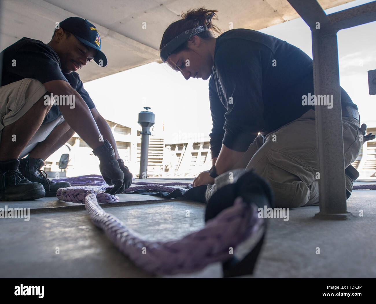 160104-N-WV703-070 ATLANTIC OCEAN (Jan. 4, 2016) Gabby Marionakis, a Deck  Midshipman, and David Leader, a civil service mariner, puts chaffing gear on the eye of a mooring line aboard USNS Spearhead (T-EPF 1) Jan. 4, 2015. The Military Sealift Command expeditionary fast transport vessel USNS Spearhead (T-EPF 1) is on a scheduled deployment to the U.S. 6th Fleet area of operations to support the international collaborative capacity-building program Africa Partnership Station. (U.S. Navy photo by Mass Communication Specialist 3rd Class Amy M. Ressler/Released) Stock Photo