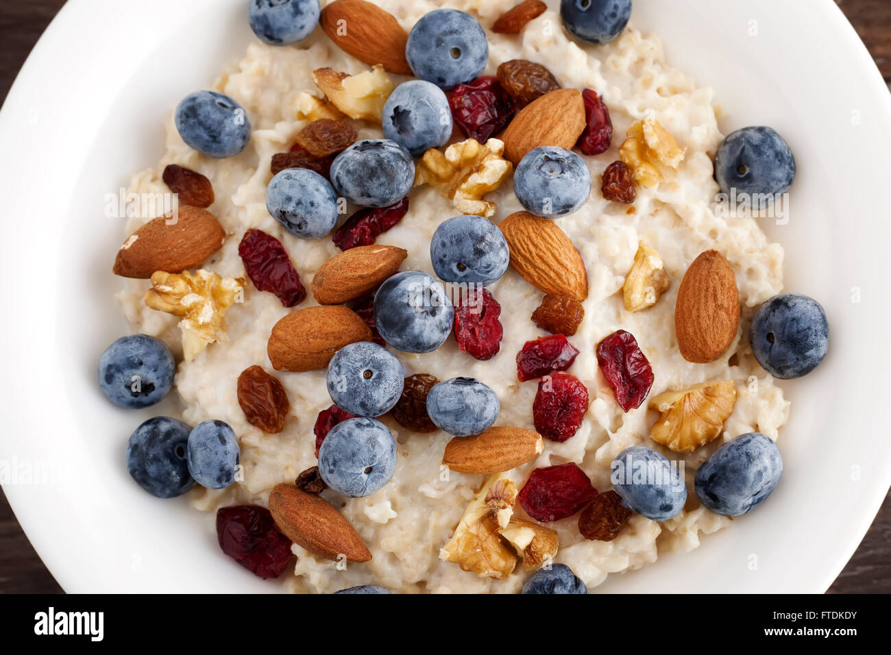 Porridge breakfast with blueberry, dried cranberries, almonds and walnuts. Stock Photo