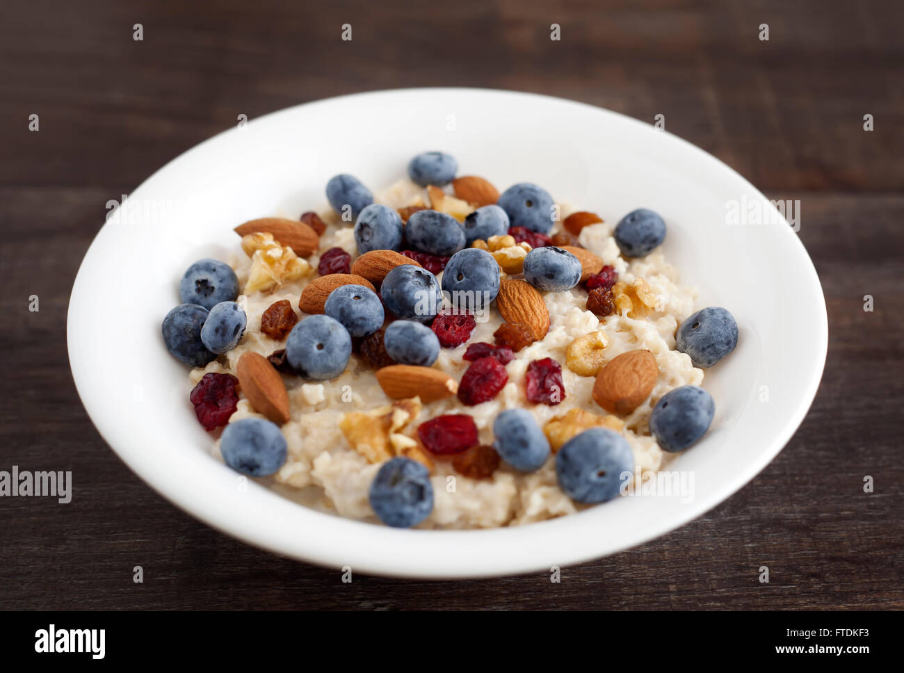Porridge breakfast with blueberry, dried cranberries, almonds and walnuts. Stock Photo