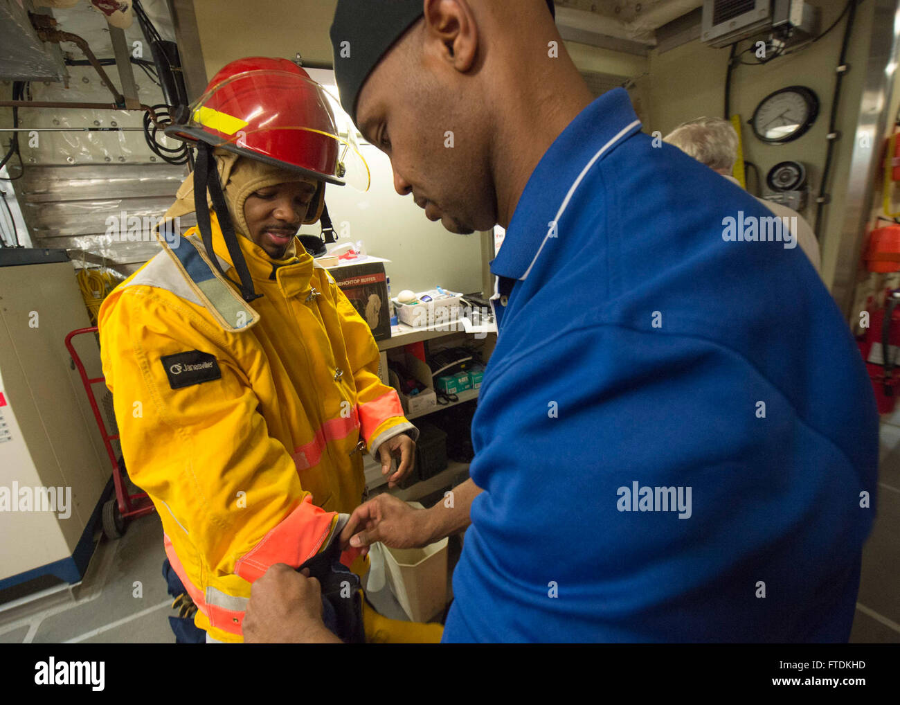 160125-N-QF605-010 ATLANTIC OCEAN (Jan. 25, 2016) - Cook Baker Irvine Cummings helps Able Bodied Seaman David Leader don his personal protective gear during a fire drill aboard USNS Spearhead (T-EPF 1) Jan. 25, 2016. The Military Sealift Command expeditionary fast transport vessel USNS Spearhead is on a scheduled deployment to the U.S. 6th Fleet area of operations to support the international collaborative capacity-building program Africa Partnership Station. (U.S. Navy photo by Mass Communication Specialist 1st Class Amanda Dunford/Released) Stock Photo