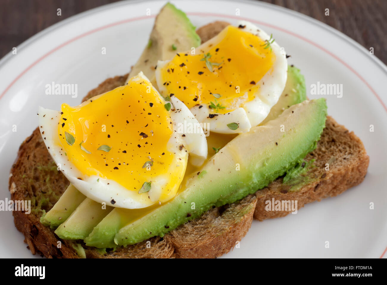 Poached egg on brown bread toast and avocado. Stock Photo