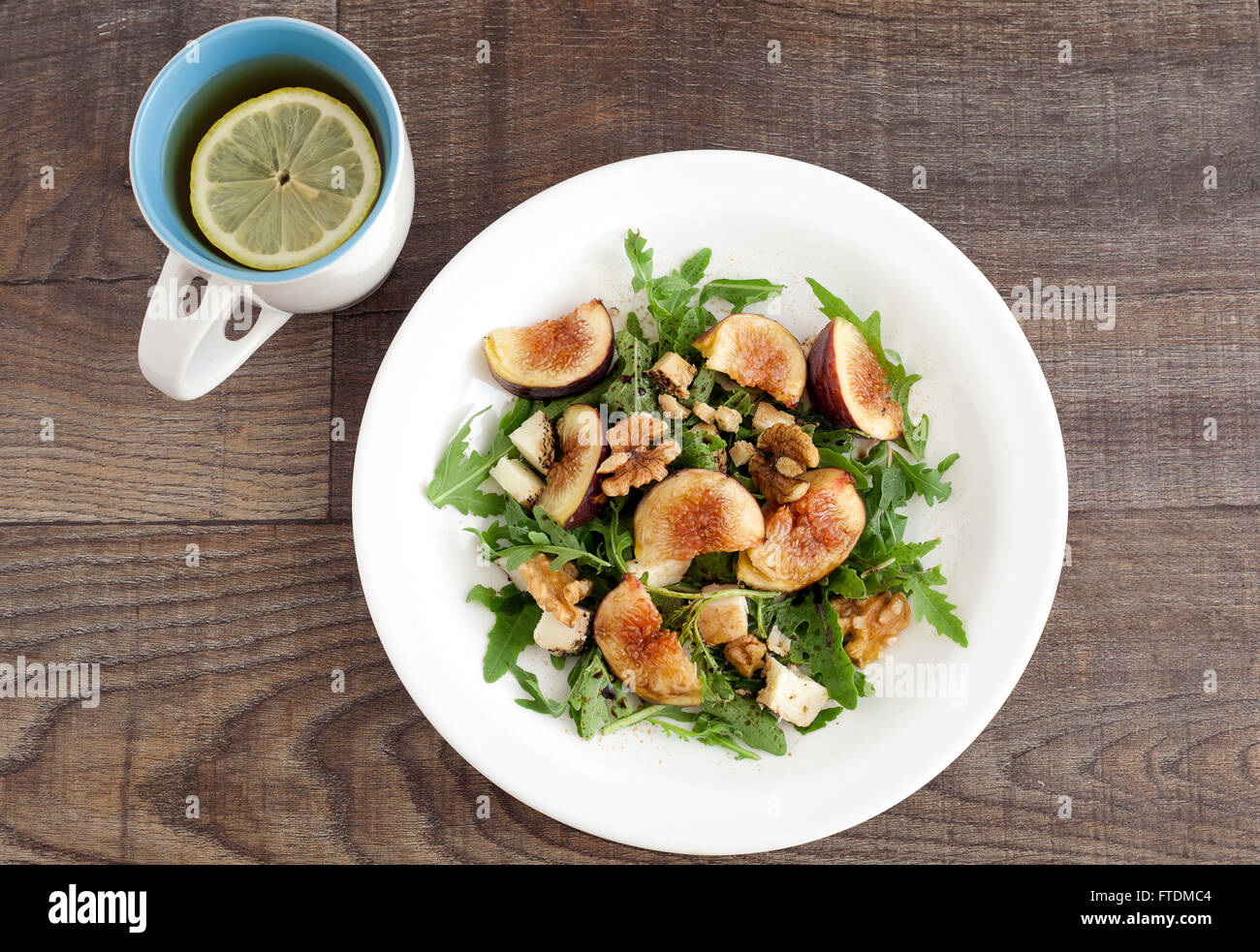 Fig with rucola, a summer mediterranean dish with lemon tea in a mug. Stock Photo