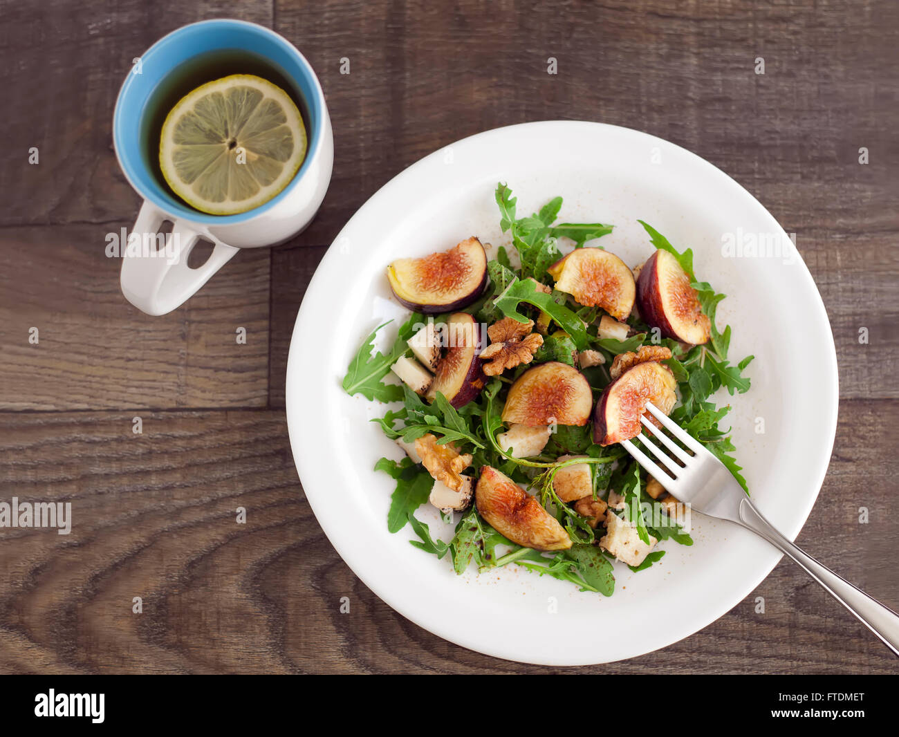 Fig with rucola, a summer mediterranean dish with lemon tea in a mug. Stock Photo