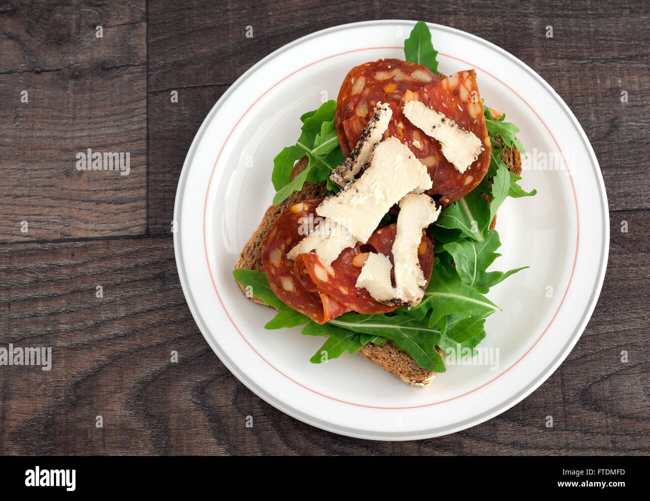 Salami sandwich with rucola, sheep cheese and brown bread. Stock Photo