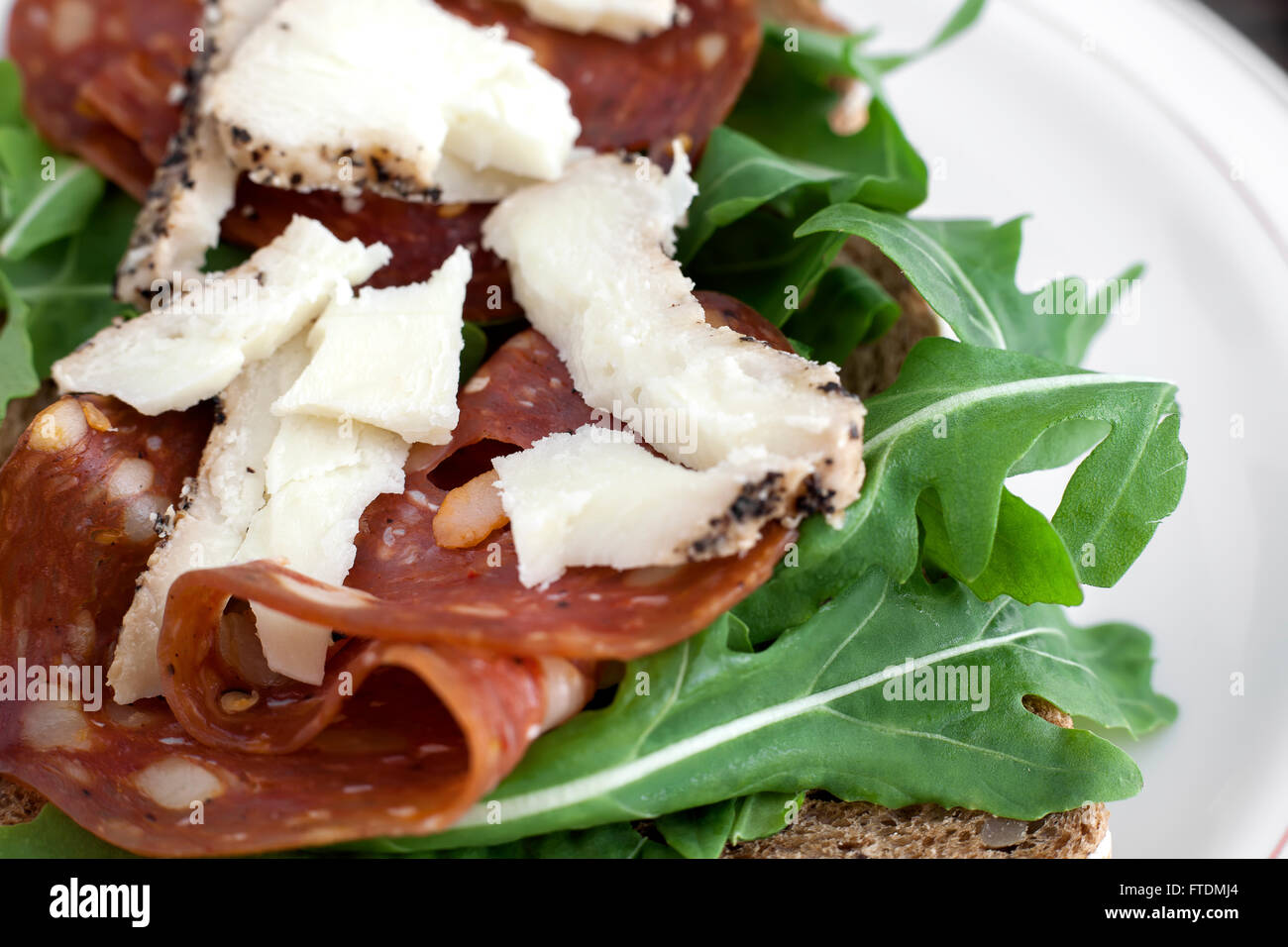 Salami sandwich with rucola, sheep cheese and brown bread. Stock Photo