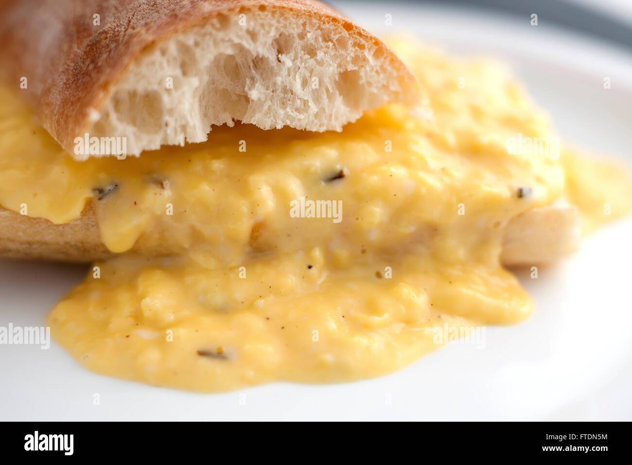 Creamy scrambled eggs with bread in French style. Stock Photo