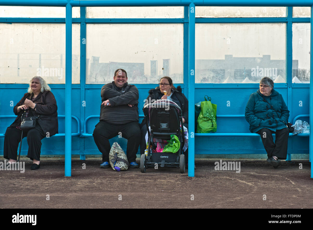 A candid image of four overweight people sitting in a beach shelter at Skegness, Lincolnshire, UK Stock Photo