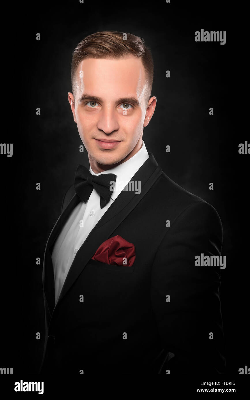 Young handsome man in black suit on dark background Stock Photo - Alamy