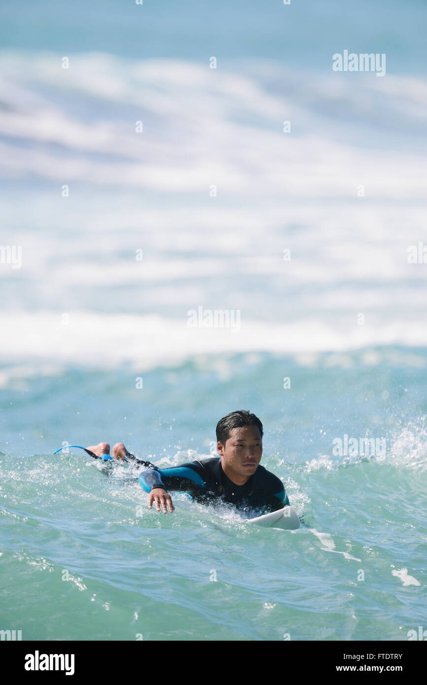 Japanese surfer paddling in the sea Stock Photo