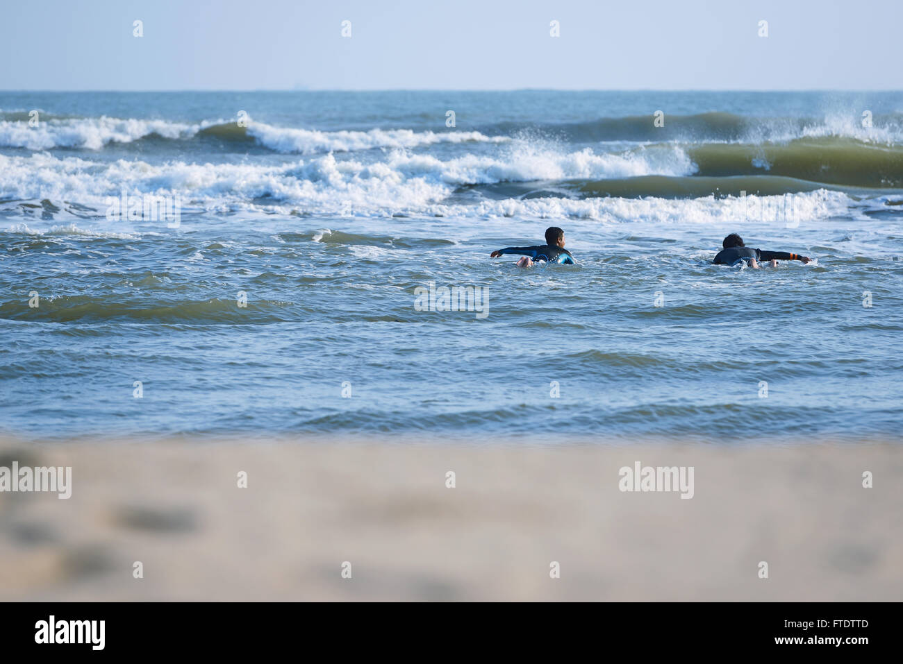 Japanese surfers paddling in the sea Stock Photo