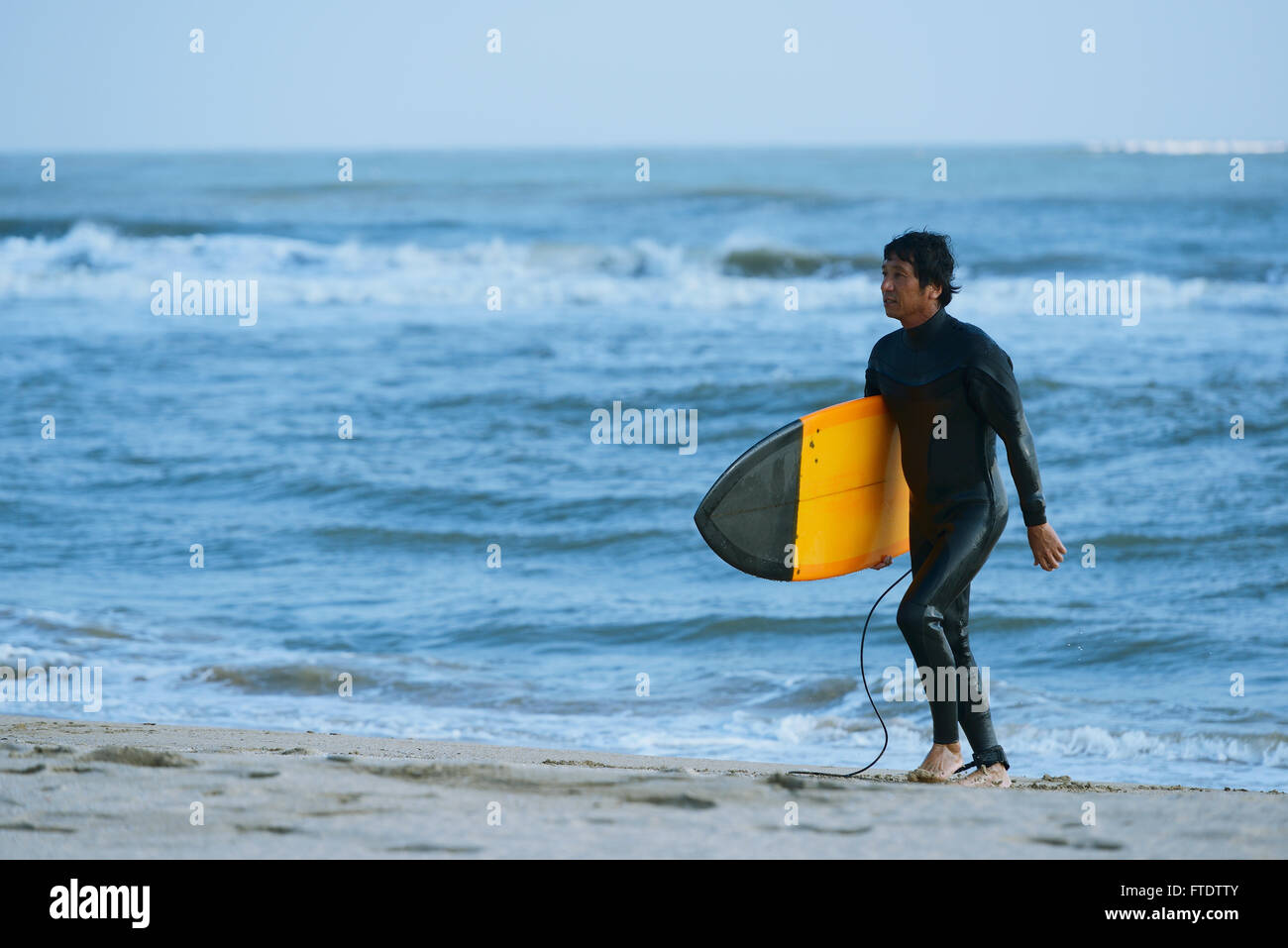 Japanese surfer walking on the beach Stock Photo