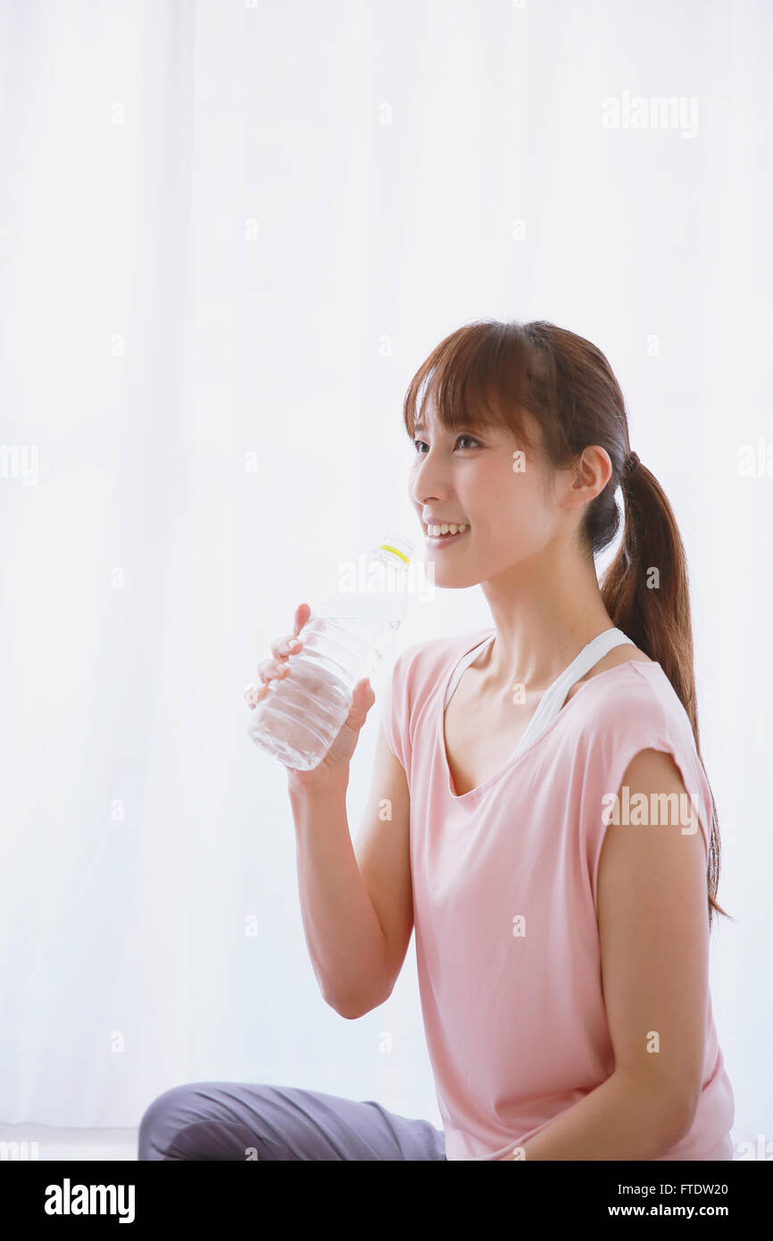 Young Japanese woman drinking water after practicing yoga Stock Photo