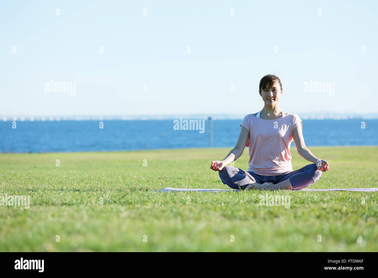 Young Japanese woman practicing yoga in a city park Stock Photo - Alamy